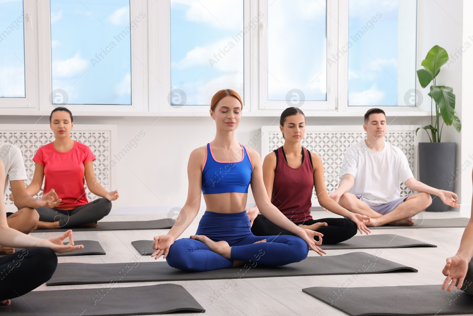 Photo of Group of people practicing yoga on mats indoors