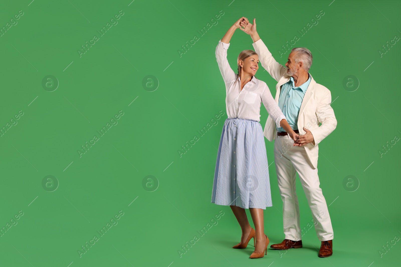 Photo of Senior couple dancing together on green background, space for text