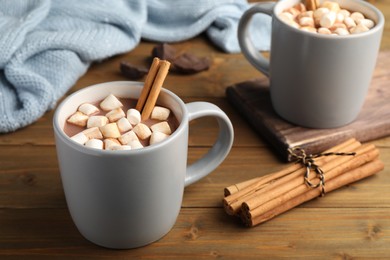 Delicious hot drink with cinnamon and marshmallows on wooden table