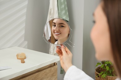 Beautiful woman looking in mirror in bathroom