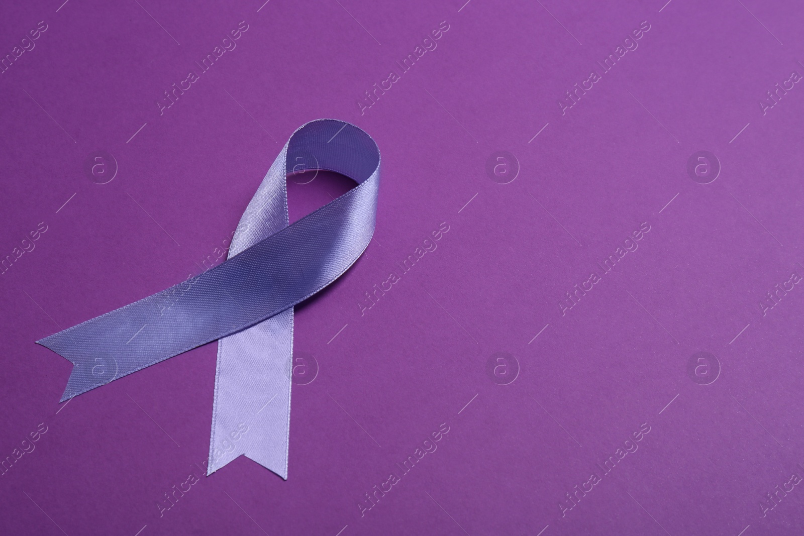 Photo of Purple awareness ribbon on color background, space for text