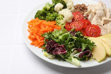 Photo of Balanced diet and healthy foods. Plate with different delicious products on white tiled table, closeup