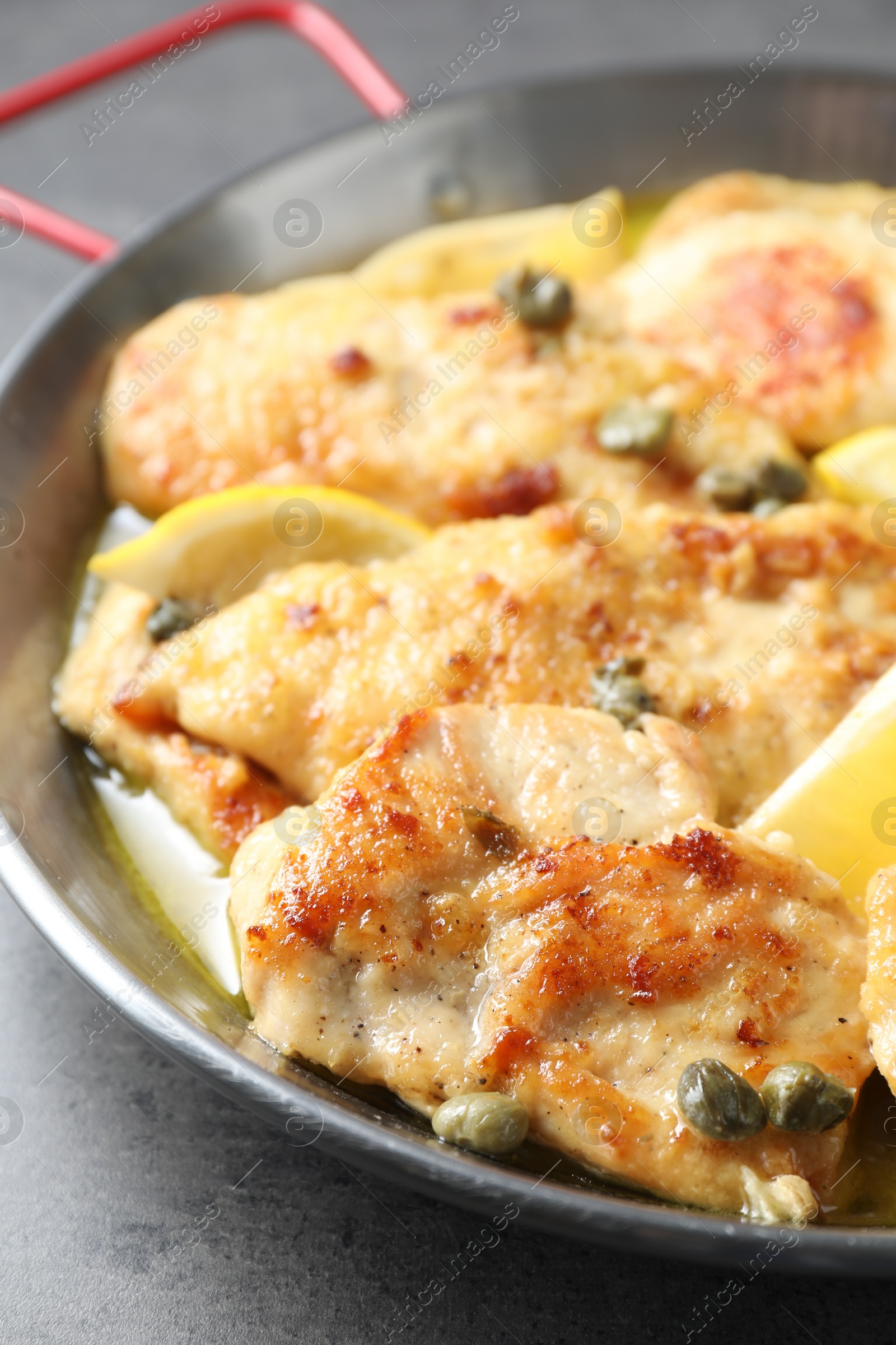 Photo of Delicious chicken piccata with lemons on grey table, closeup