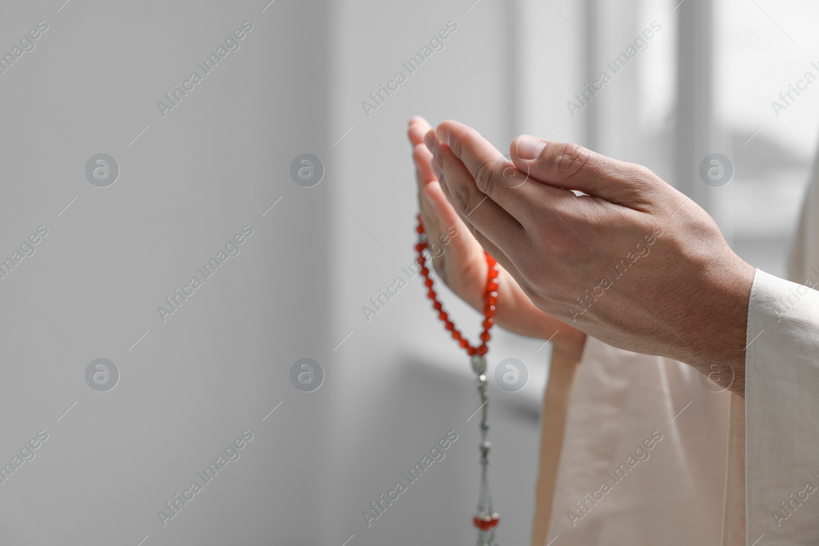 Photo of Muslim man with misbaha praying indoors, closeup. Space for text