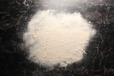 Photo of Pile of flour on black marble table, top view