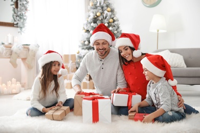 Happy family with children and Christmas gifts on floor at home