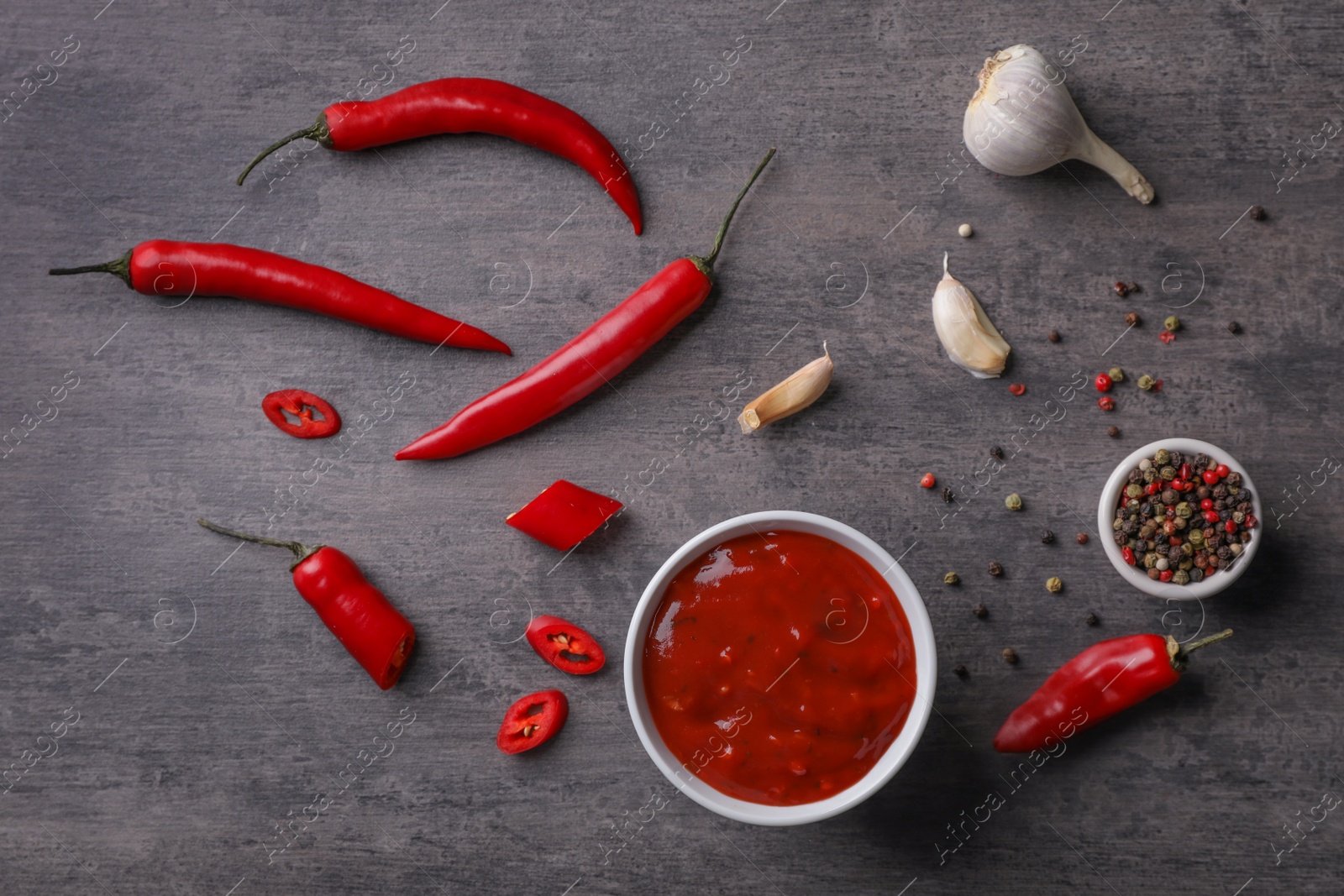 Photo of Flat lay composition with chili sauce and different spices on dark background