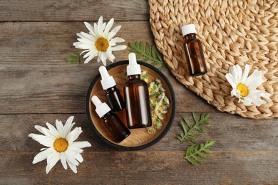 Photo of Flat lay composition with essential oil and flowers on wooden background