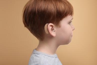 Photo of Little boy with hearing aid on pale brown background