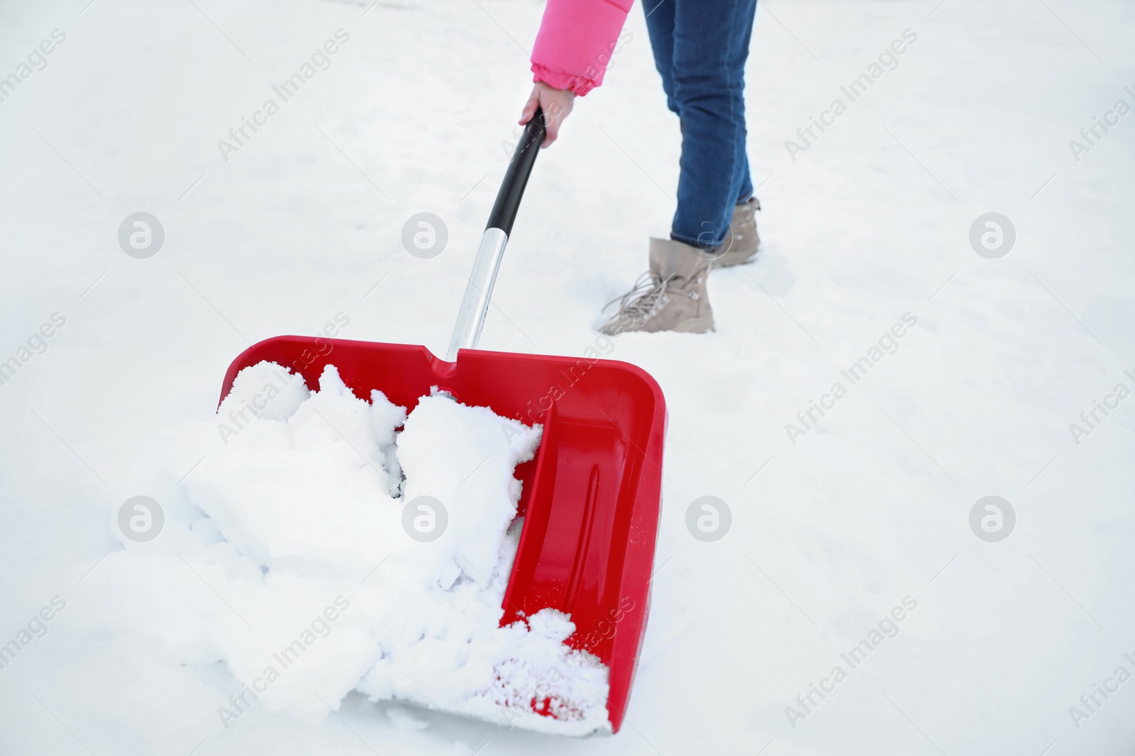 Photo of Woman cleaning snow with shovel outdoors on winter day, closeup