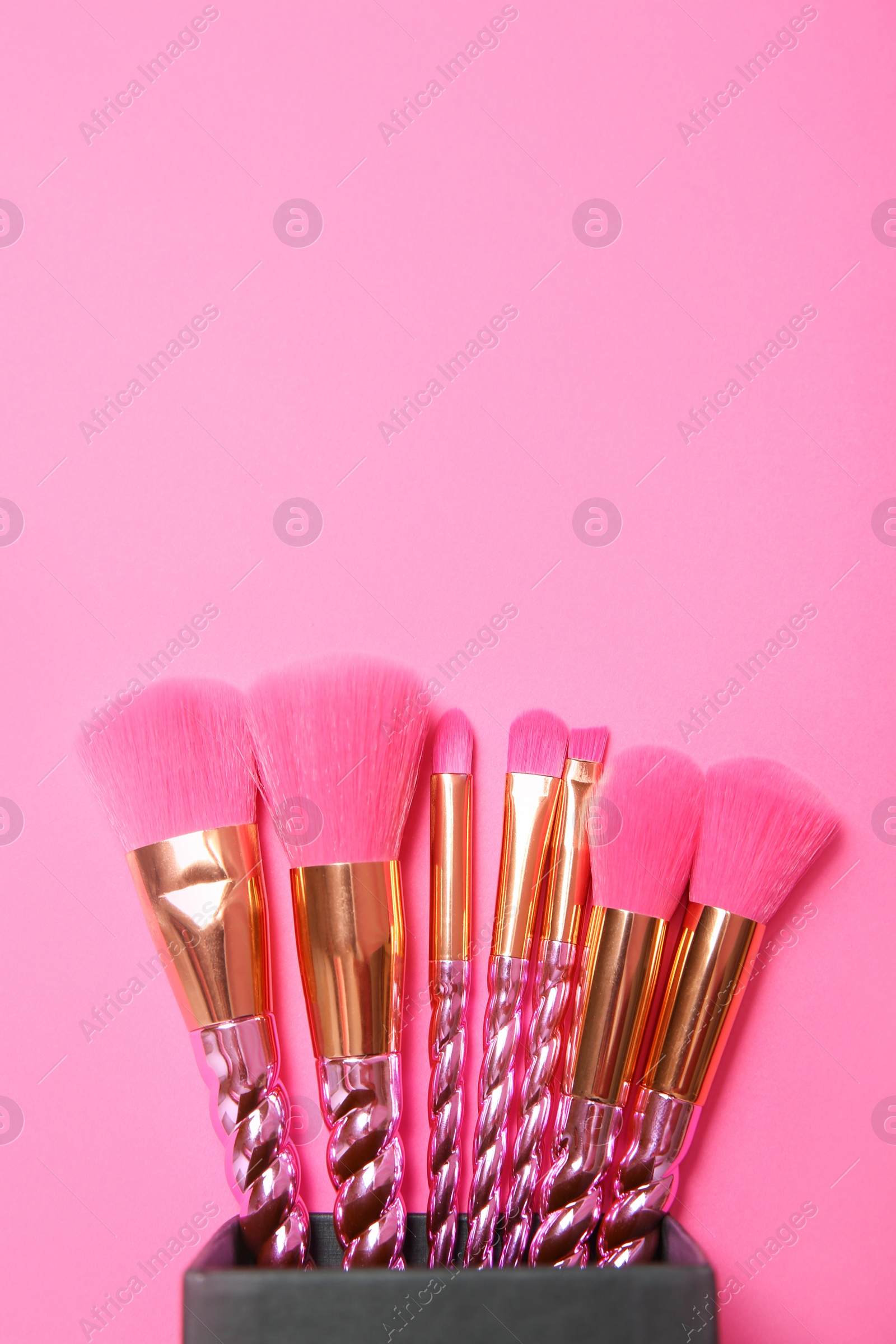 Photo of Organizer with set of makeup brushes on pink background, top view. Space for text