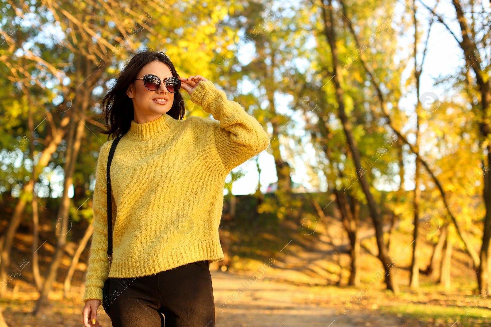 Photo of Beautiful young woman wearing stylish sweater in autumn park