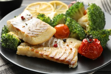 Photo of Tasty cod cooked with vegetables served on table, closeup