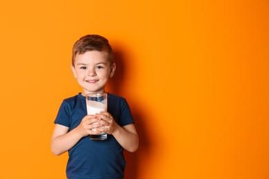 Cute little boy with glass of milk on color background