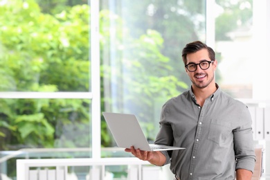 Handsome young man working with laptop indoors