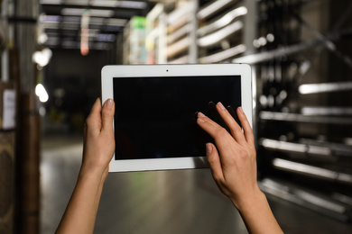 Woman with tablet in wholesale warehouse, closeup. Space for design