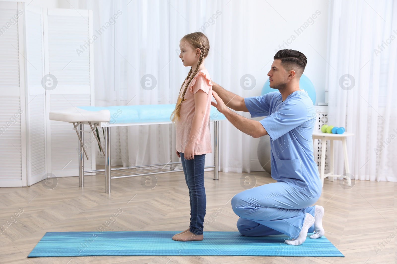 Photo of Orthopedist examining child's back in clinic. Scoliosis treatment