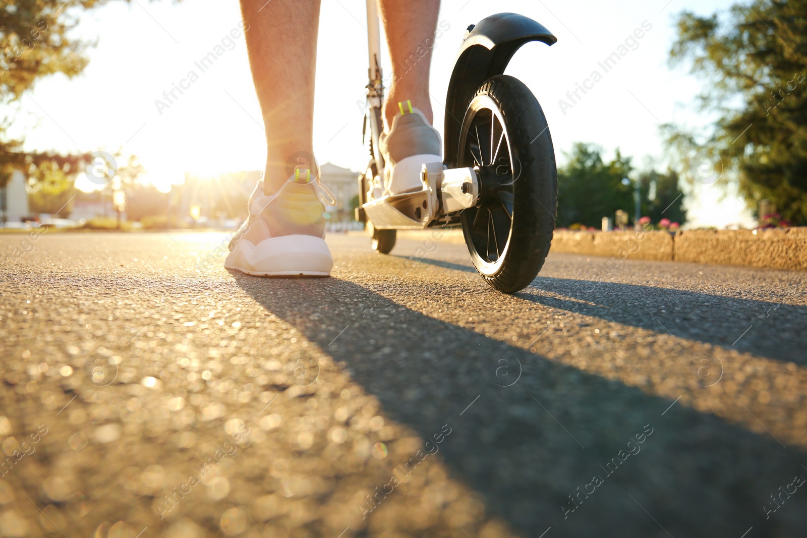 Photo of Man riding modern kick scooter in park, closeup