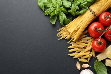 Different types of pasta, spices and products on black background, flat lay. Space for text