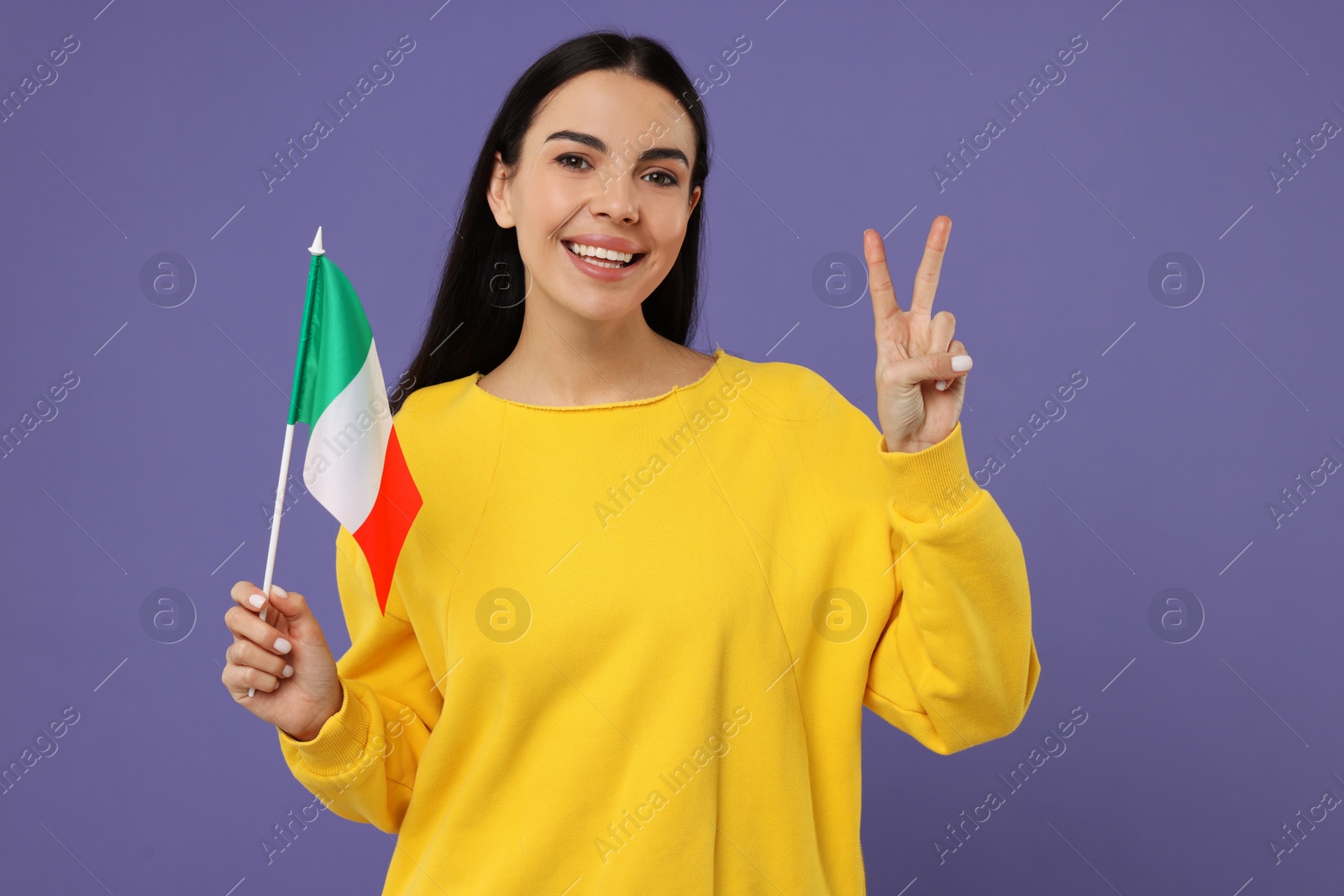 Photo of Happy young woman with flag of Italy showing V-sign on violet background