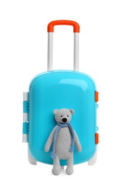 Photo of Stylish little blue suitcase with teddy bear on white background