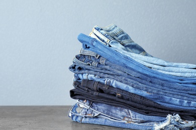 Photo of Stack of jeans on table against grey background