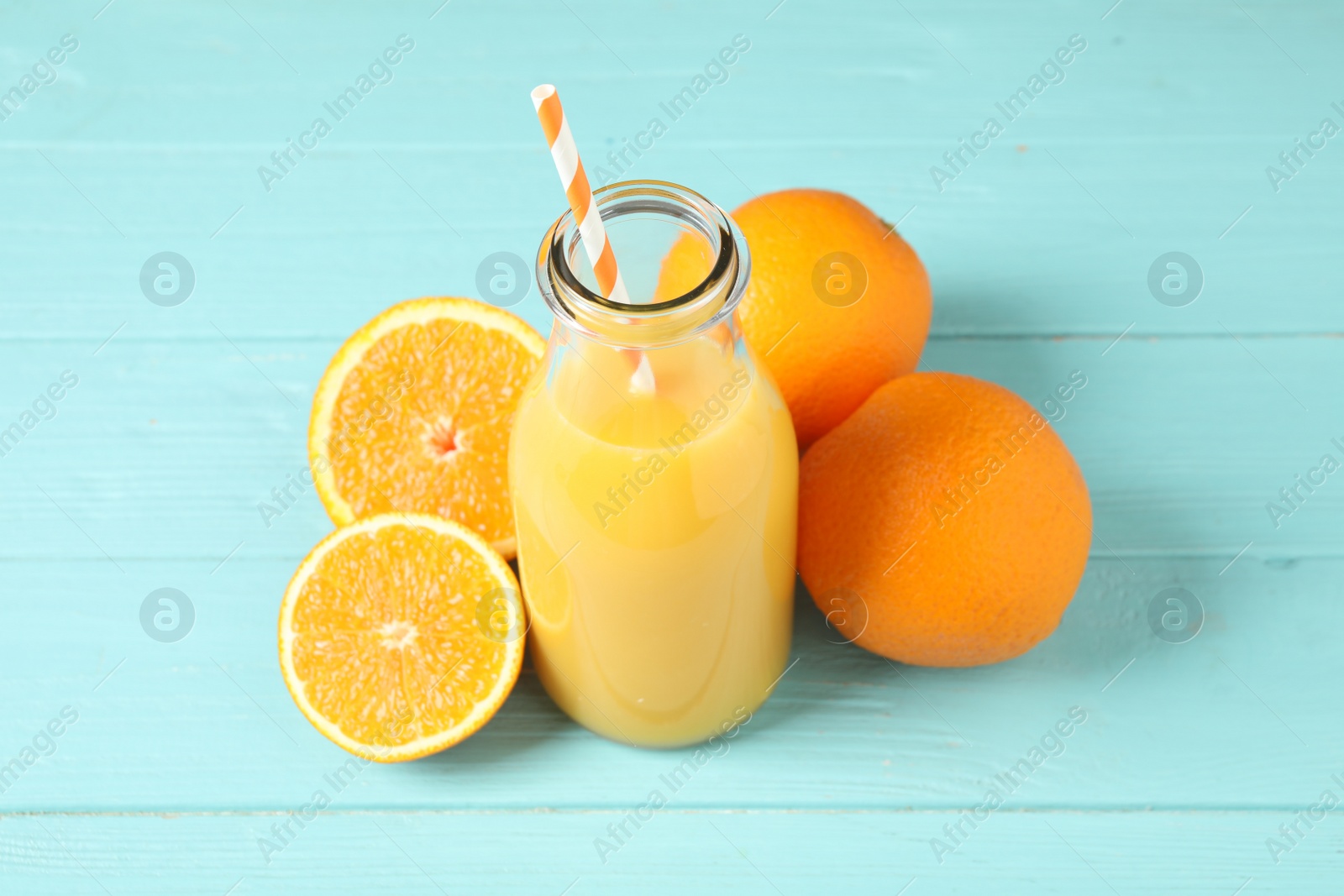 Photo of Bottle of orange juice and fresh fruits on light blue wooden table