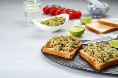 Photo of Delicious sandwiches with guacamole on white wooden table. Space for text