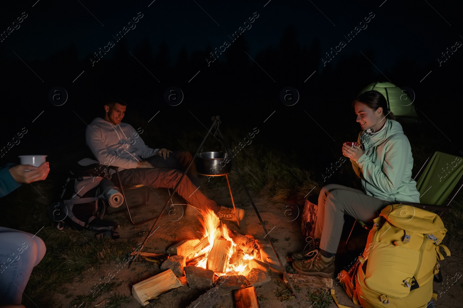 Photo of People sitting near bonfire in camp at night