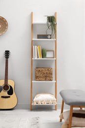 Spring atmosphere. Wooden shelving unit with accessories near acoustic guitar in stylish room