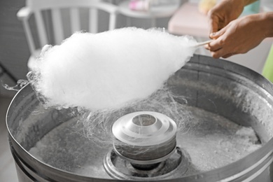 Photo of Woman making cotton candy using modern machine indoors, closeup