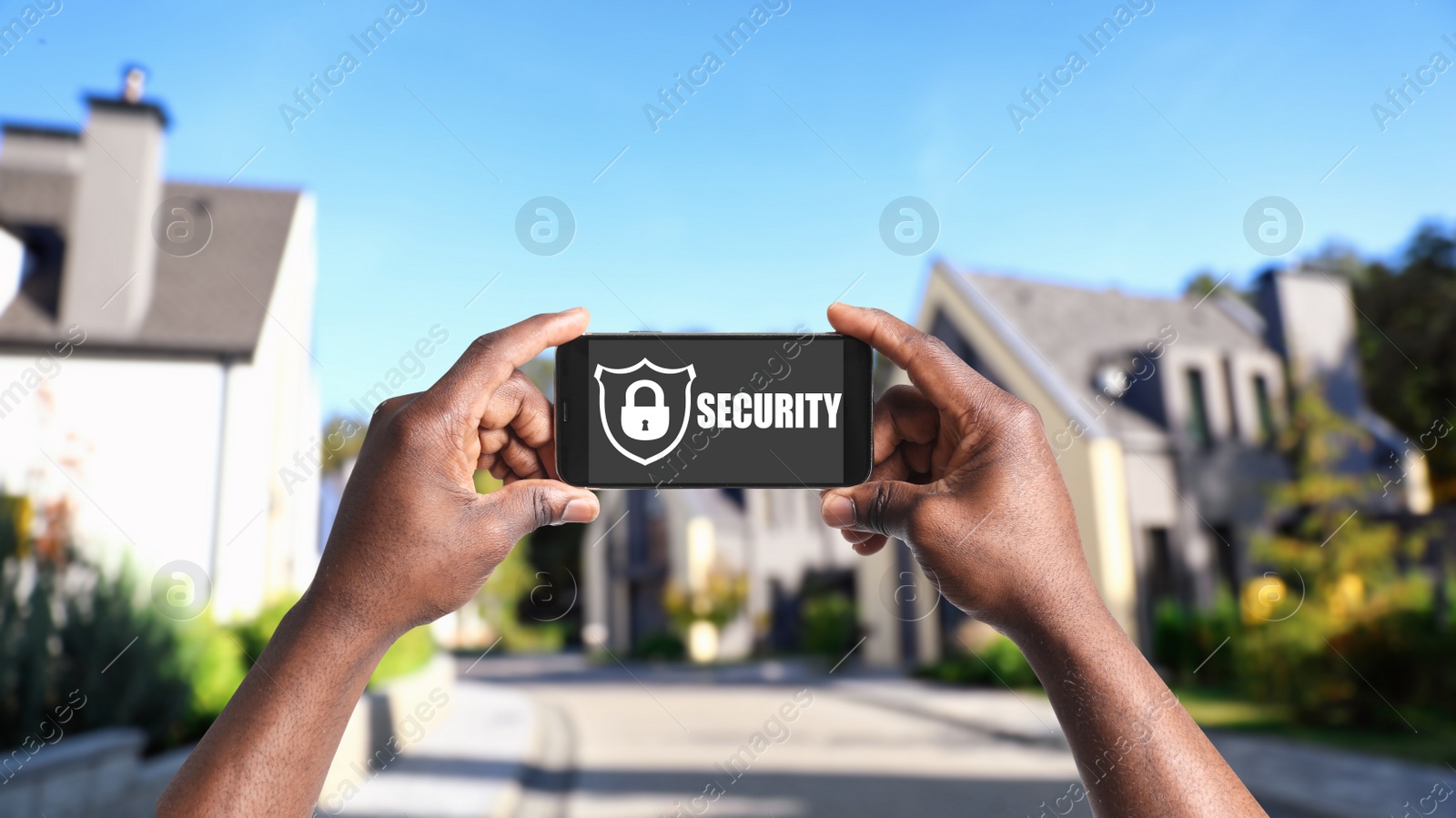 Image of Alarm system. African American man using phone outdoors, closeup