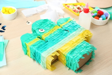 Photo of Bright cardboard cactus and materials on wooden table. Pinata diy