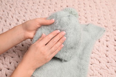Photo of Woman touching soft knitted hat, closeup view