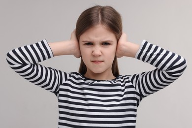 Photo of Hearing problem. Little girl suffering from ear pain on grey background