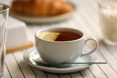 Photo of Cup of aromatic tea with lemon on table, closeup