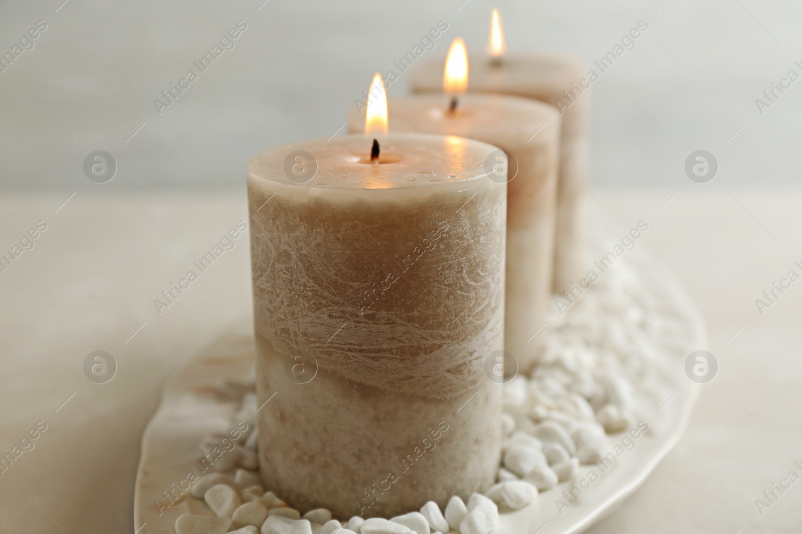 Photo of Plate with three burning candles and rocks on table