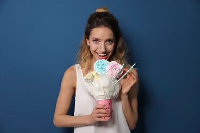 Photo of Portrait of young woman holding cotton candy dessert on blue background