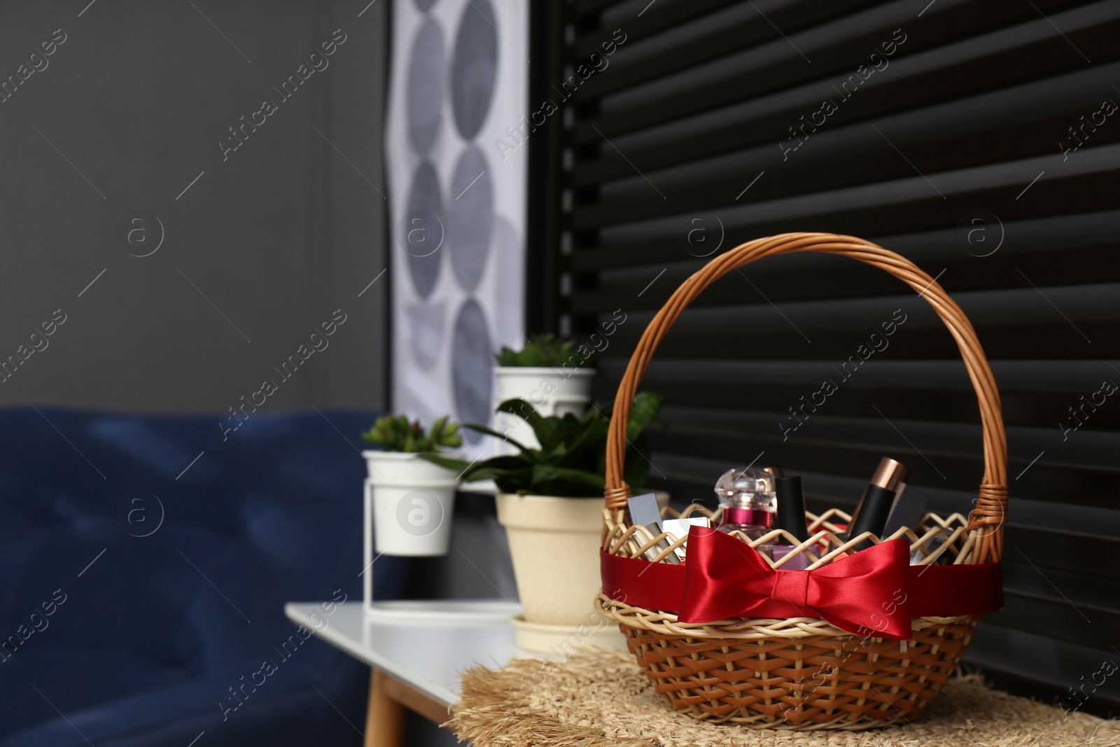 Photo of Wicker gift basket with cosmetic products on table indoors