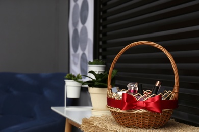 Wicker gift basket with cosmetic products on table indoors