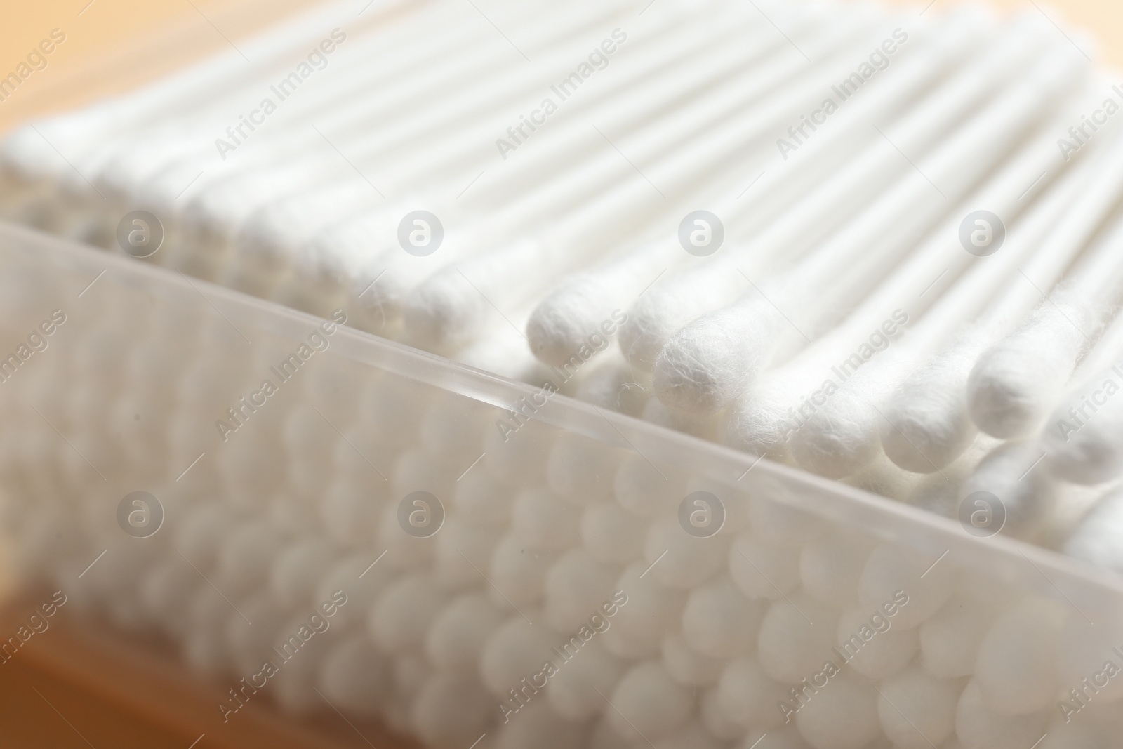 Photo of Plastic container with cotton swabs on color background, closeup