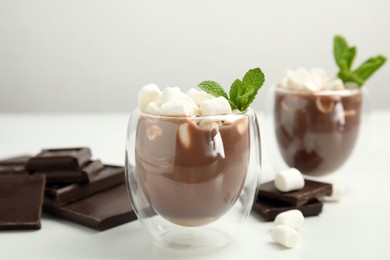 Photo of Glasses of delicious hot chocolate with marshmallows and fresh mint on white table