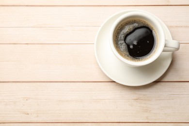 Photo of Cup of aromatic coffee on light wooden table, top view. Space for text