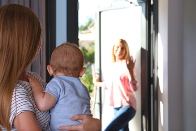 Photo of Mother leaving her baby with teen nanny at home. Space for text