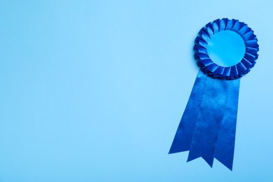 Photo of Blue award ribbon on turquoise background, top view. Space for text