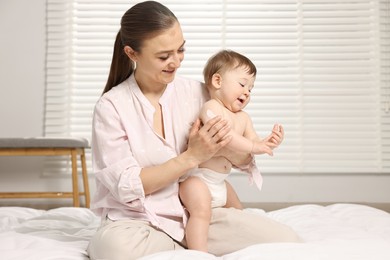 Photo of Happy mother applying body cream onto baby`s skin at home