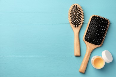 Photo of Hair brushes and balm on light blue wooden table, flat lay. Space for text
