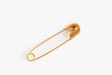 Photo of Golden safety pin on white background, top view