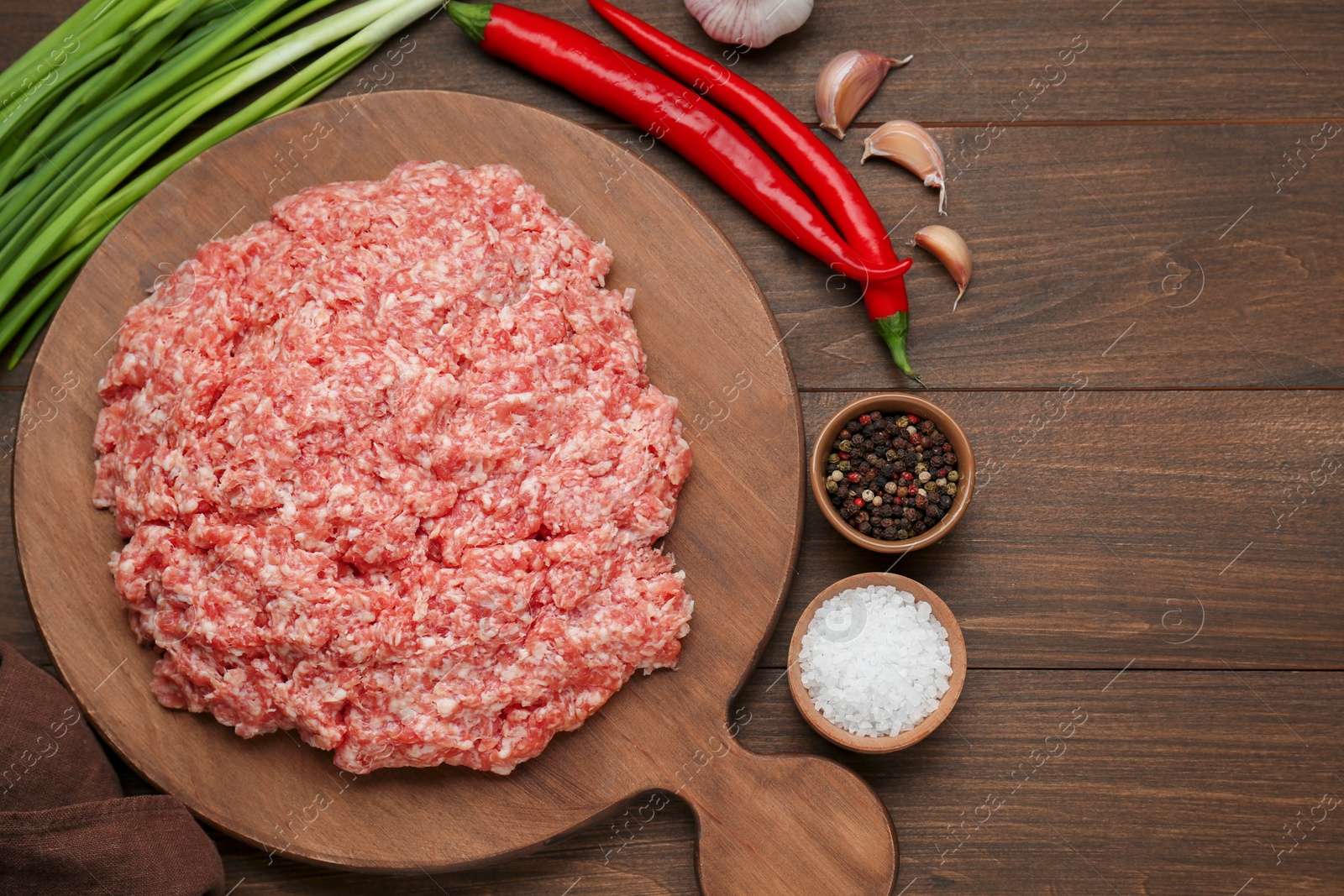 Photo of Raw fresh minced meat and ingredients on wooden table, flat lay. Space for text