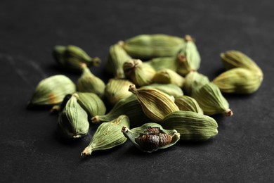 Pile of dry cardamom pods on black table, closeup